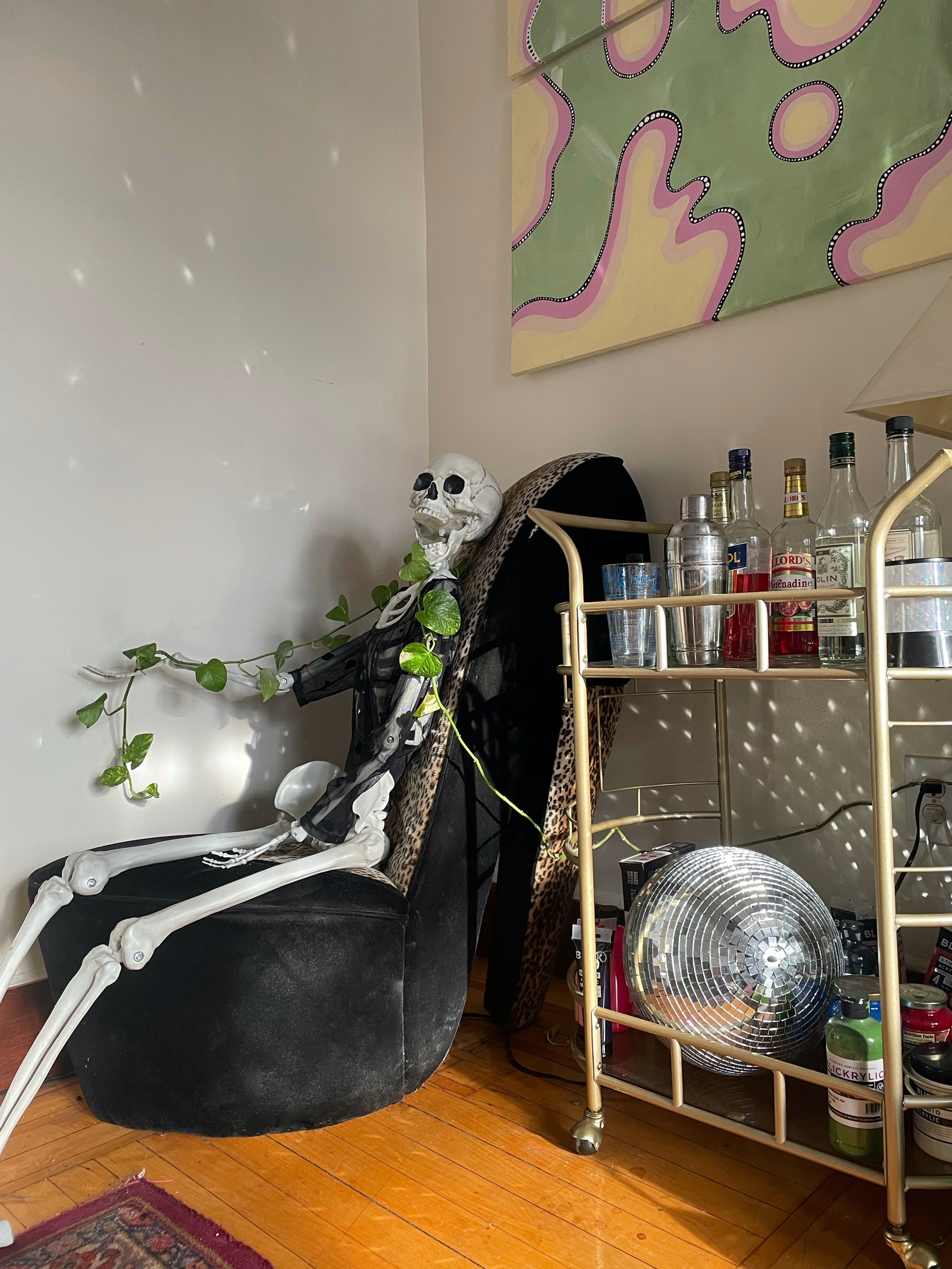 Une chaise à chaussures à talons hauts à côté d'un chariot de bar et d'une boule disco dans la chambre à coucher de Katie Harless à Brooklyn.